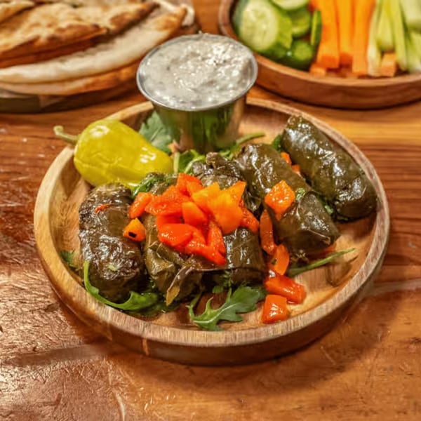 Grape leaves stuffed with rice and herbs, topped with diced red peppers, served with tzatziki.